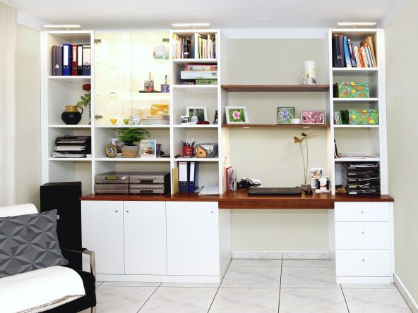 Weiße Möbel mit dunklen Holzelementen als Platzsparende Kombination aus Schreibtisch und Regal.